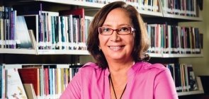 Retrato da colunista Regina Scarpa com livros ao fundo