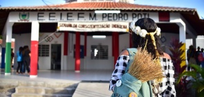 Mulher indígena anda em direção a escola