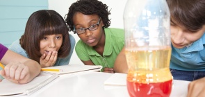 Alunos observam garrafa com experimento em aula de ciências