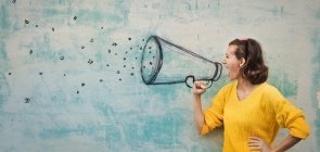 Mulher faz a expressão de estar gritando. Na parede de fundo está desenhado um megafone