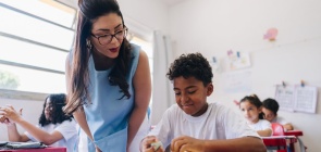 Professora conversando com estudante em sala de aula