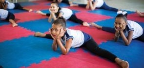 Abrindo espacate, vemos um grupo de meninas com o rosto apoiado nas mãos olhando para a câmera