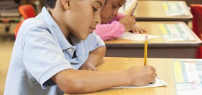 aluno sentado na cadeira escrevendo na prova