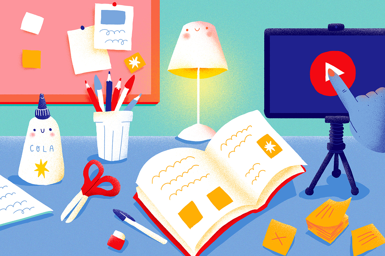 Ilustra&ccedil;&atilde;o de mesa de um professor com livros, cadernos, folhas, cola e outros objetos de trabalho. Um celular em um trip&eacute; a frente mostra um bot&atilde;o de play.