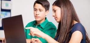 Um menino e um menina debatem sobre algo que observam em um computador
