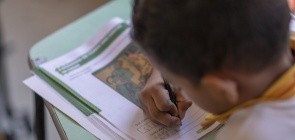 Menino debruçado sobre caderno de atividades em Aracati (CE)