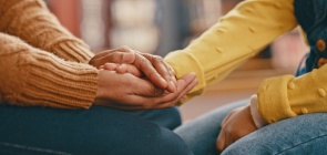 Mãos de uma pessoa adulta seguram as mãos de uma criança
