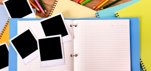 Fotos em branco sobre um caderno aberto com um fundo azul e amarelo, com lápis de cores.