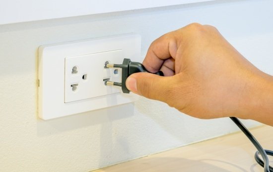 Homem encaixa um fio da tomada