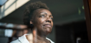 Uma senhora olha para fora através de uma janela