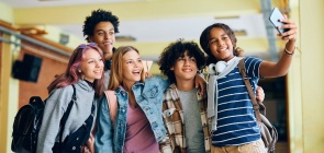 Grupo de adolescentes, com mochilas e cadernos, faz pose para uma selfie