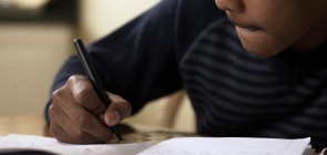 Foto de um aluno adolescente escrevendo 