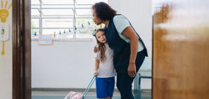 Foto de uma professora abraçando uma aluna na porta de sala de aula