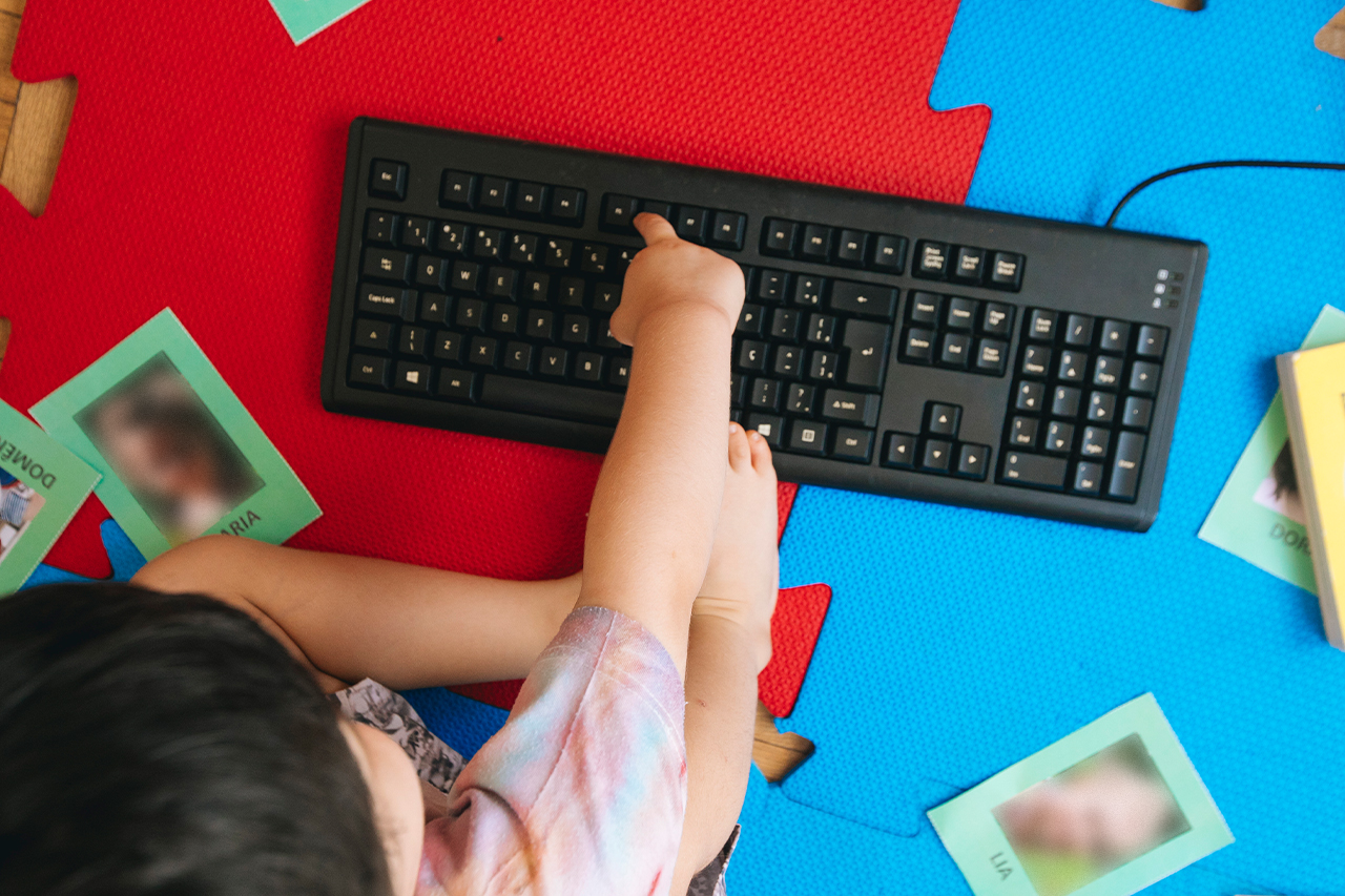 Fotografia de aluno da Educa&ccedil;&atilde;o Infantil, brincando com teclado de computador.