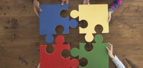 Quatro pessoas seguram uma peça de um quebra-cabeça colorida