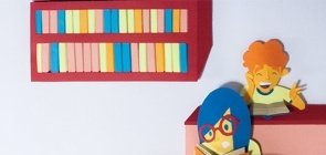 Ilustração. À direita há tres fileiras em cada uma um aluno segurando um livro. No fundo da sala há uma estante cheia de livros