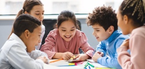 Um grupo de cinco crianças olham atentos para o celular na mão de uma delas