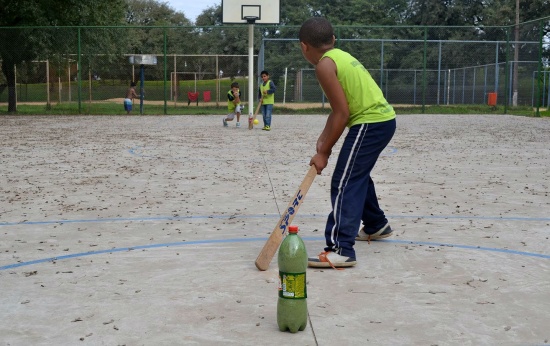 Garotos jogando taco em quadra de escola