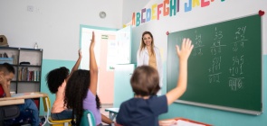 Uma professora branca dá aula para uma turma de crianças