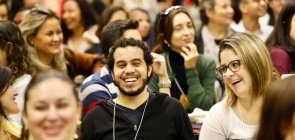 várias pessoas sentadas em uma espécie de auditório sorrindo