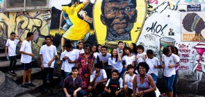 Uma turma de estudantes reunidos em frente ao mural graffitado de Zumbi dos Palmares