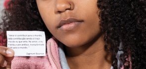 Aluna segura papel com frase do Bauman sobre amor