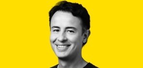 Fundo amarelo, foto em branco e preto. Homem entre 30 e 40 anos, de cabelo curto, sorrindo. 