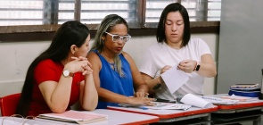Três professoras fazem atividade juntas durante formação continuada na escola