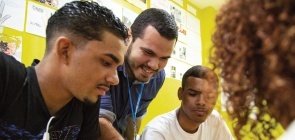 Grupo de jovens olham para celular apoiado na mesa