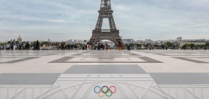 Foto colorida de pódio nas Olimpíadas de Paris, com Torre Eiffel ao fundo