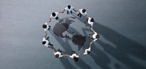 Crianças em circulo dando a mão, no centro há um mapa dos continentes