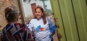Mulher no centro conversa na porta com senhora