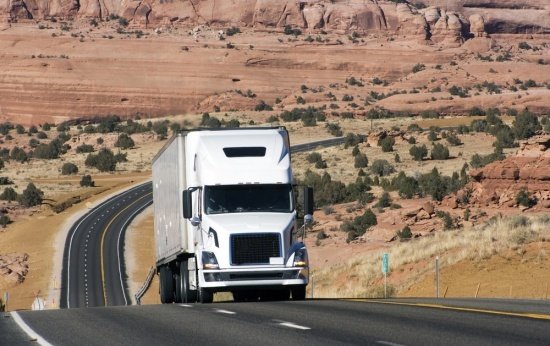 Caminhão trafega sozinho por estrada em uma paisagem de deserto