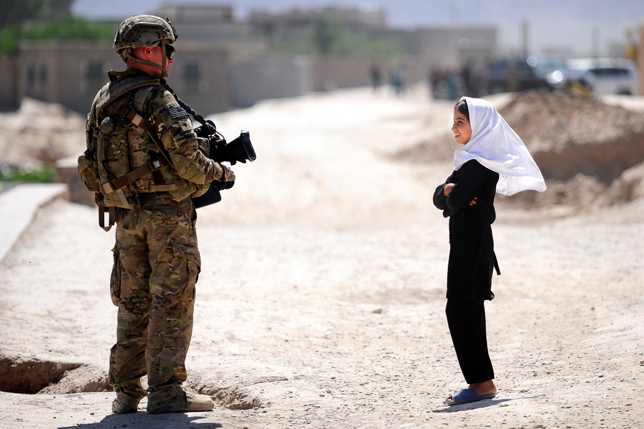 Soldado americano conversa com garota afeg&atilde; enquanto patrulha a prov&iacute;ncia de Farah. Departamento de Defesa dos Estados Unidos, Maio de 2012.
