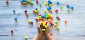 Criança segura balas coloridas