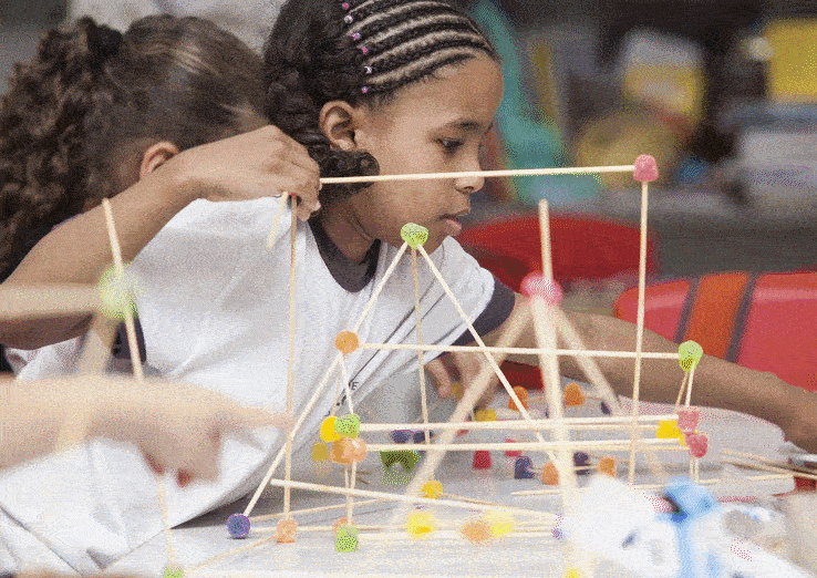 Ilustra&ccedil;&atilde;o de aluna utilizando modelos matem&aacute;ticos e maquetes do sistema solar.