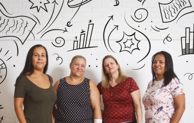 Equipe gestora posa em pé para a foto. Ao seu redor, ilustração de gráficos, tabelas e checklists dão o clima da avaliação.