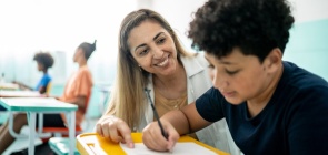 Professora, conversa e ajuda aluno na sala de aula