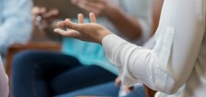 Foto mostra detalhe de um gesto de mão durante uma reunião
