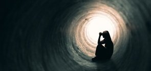 Menina sentada dentro de um túnel escuro