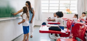 professora e uma aluna fazendo atividade na lousa