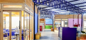 Foto de uma escola sustentável, com uma arquitetura diferenciada, feita com madeira e materiais sustentáveis