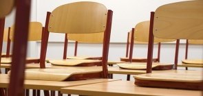 Uma fileira de carteiras sem alunos