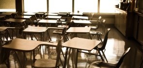 Cadeiras de sala de aula vazias e amontoadas em uma sala com luz indireta