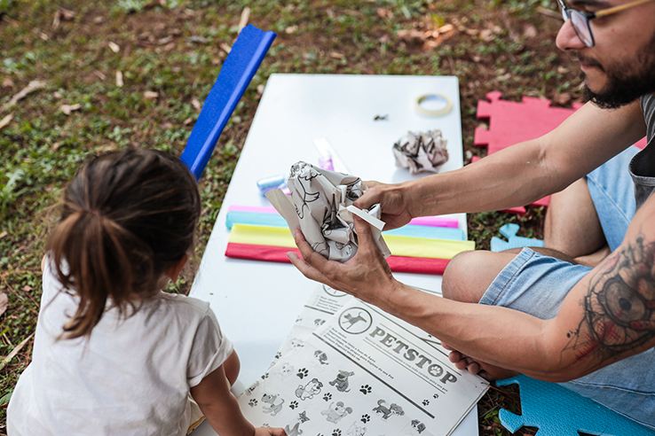 Fotografia de crian&ccedil;a brincando com pap&eacute;is e materiais de largo alcance em um parque.