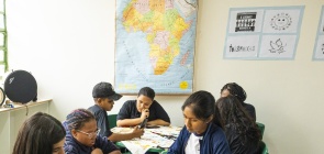 Alunos fazem atividades com carimbos adinkras. Ao fundo, um mapa do continente africano