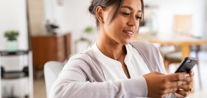Uma mulher sentada em um sofá enquanto manuseia um celular