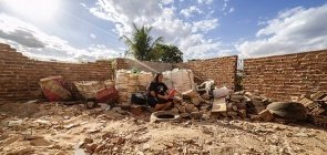 Mulher lê livro em cima de entulho de lixo
