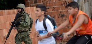 Alunos passam por fuzileiros Navais durante operação na favela Kelson's, zona norte do Rio de Janeiro