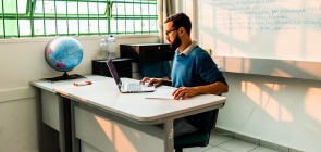 Professor, sentado em frente ao notebook, fazendo anaotações